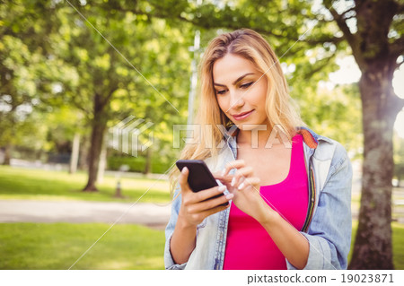 Smiling woman using smartphone in park Smiling woman using smartphone in park 19023871