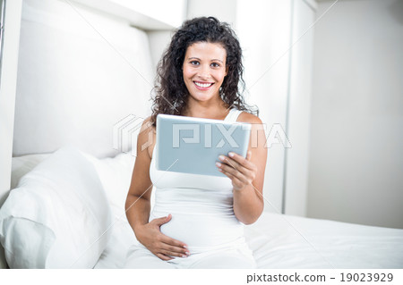 Portrait of beautiful pregnant woman using digital tablet Portrait of beautiful pregnant woman using digital tablet 19023929