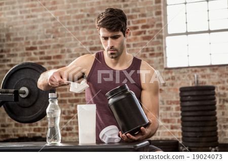 Man adding supplement from tin to bottle Man adding supplement from tin to bottle 19024073