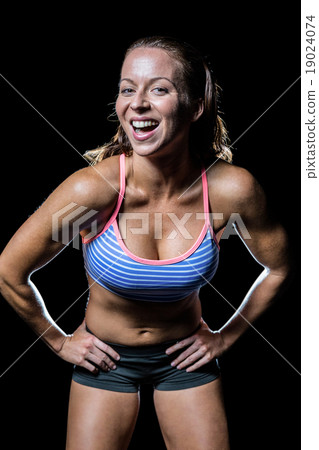 Portrait of cheerful female athlete with hand on hip 19024074