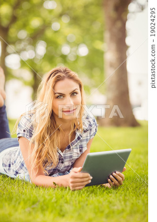 Portrait of smiling woman holding digital tablet at park Portrait of smiling woman holding digital tablet at park 19024295