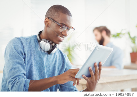 Stock Photo: Smiling man with headphones while using digital tablet