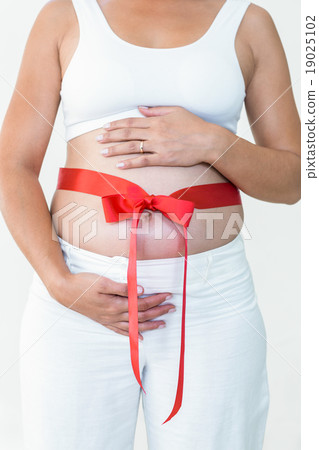 Midsection of pregnant woman with a red ribbon around her bump Midsection of pregnant woman with a red ribbon around her bump 19025102