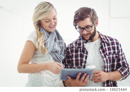 Smiling man and woman working on digital tablet 19025484