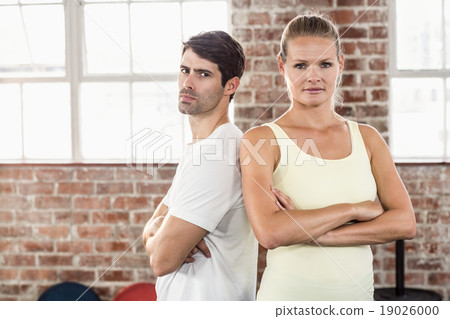 Fit couple with arms crossed in bright exercise room 19026000