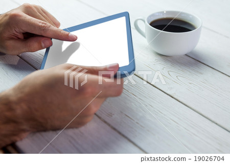 Person holding tablet on wooden desk 19026704