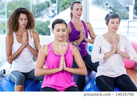 Women relaxing on exercise balls with joined hands 19026798