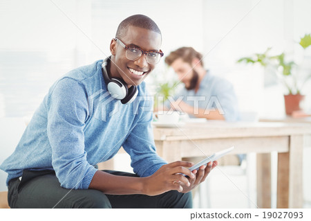 Stock Photo: Portrait of smiling man with headphones while using digital tabl