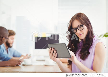 Thoughtful woman holding digital tablet at desk 19027460