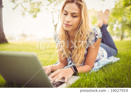 Woman using laptop while lying on grass Woman using laptop while lying on grass 19027959
