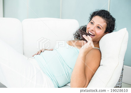 Pregnant woman eating chocolate bar Pregnant woman eating chocolate bar 19028610