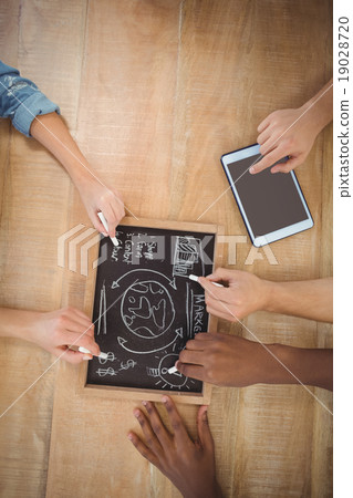Overhead view of cropped hands writing business terms on slate w 19028720