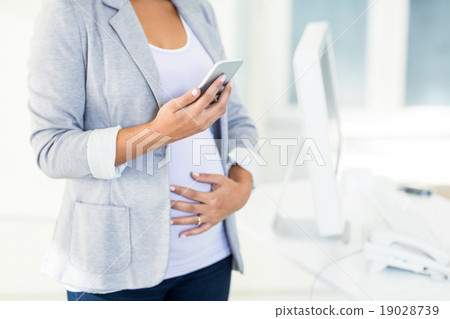 Pregnant businesswoman using phone Pregnant businesswoman using phone 19028739