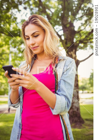 Happy woman using smartphone in park 19028981