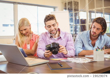 Businesswoman looking at camera with colleagues working 19029074