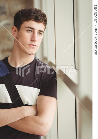 Close-up of thoughtful male student leaning on window Close-up of thoughtful male student leaning on window 19029081