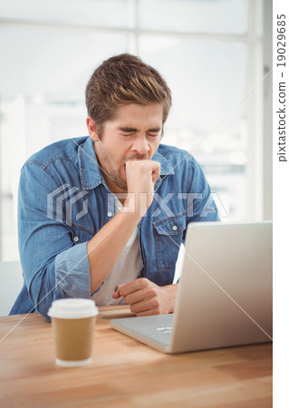 Businessman yawning while sitting at desk Businessman yawning while sitting at desk 19029685