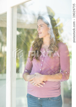 Happy woman standing by glass window Happy woman standing by glass window 19029735