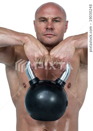 Portrait of confident man lifting kettlebell 19030248