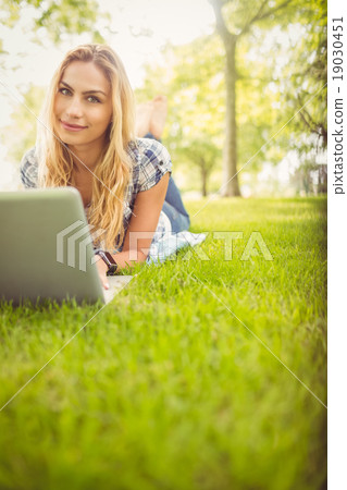 Portrait of smiling woman using laptop while lying on grass 19030451
