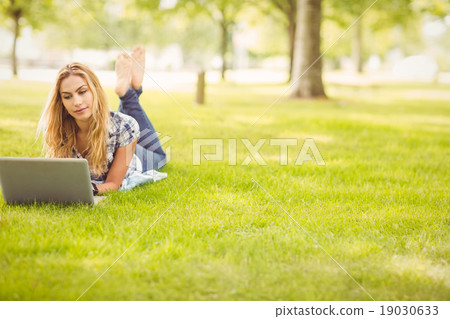 Full length of woman using laptop while lying on grass Full length of woman using laptop while lying on grass 19030633