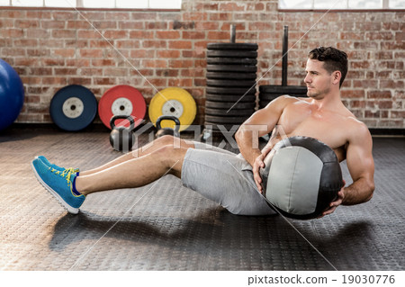 Shirtless man exercising with medicine ball 19030776