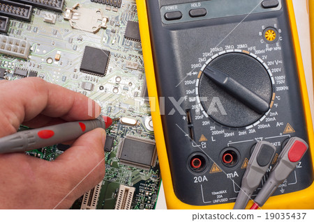 Engineer examining motherboard by multimeter 19035437