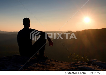 Hiker take relaxing on a rock and enjoying sunset 19047519