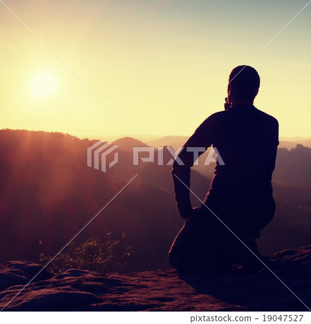 Hiker take relaxing on a rock and enjoying sunset  19047527