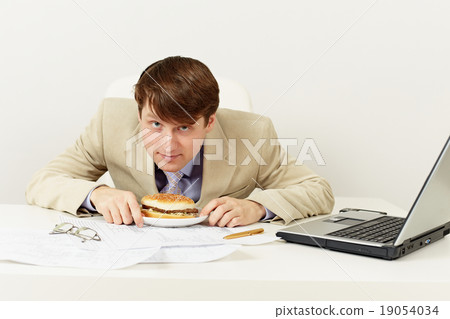 Young businessman is going to have dinner hamburger at office Young businessman is going to have dinner hamburger at office 19054034