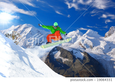Snowboarder jumping against blue sky 19064331