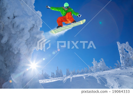 Snowboarder jumping against blue sky Snowboarder jumping against blue sky 19064333