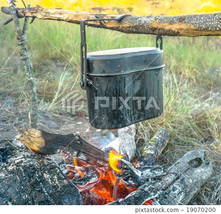 Preparing food on campfire in wild camping Preparing food on campfire in wild camping 19070200