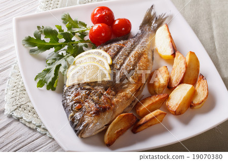 dorado fish with fried potatoes and lemon closeup dorado fish with fried potatoes and lemon closeup 19070380