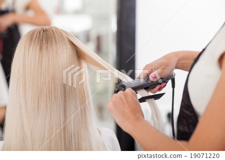 Professional hairstylist is working with iron 19071220