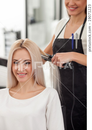 Cheerful female hairdresser is working with 19071223
