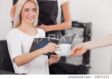 Cheerful female hairdresser is serving her 19071233