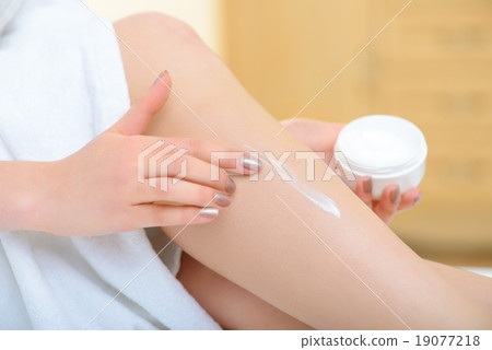 Young girl is putting body lotion on. 19077218