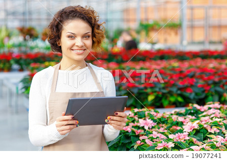 Smiling florist holding a tablet. 19077241
