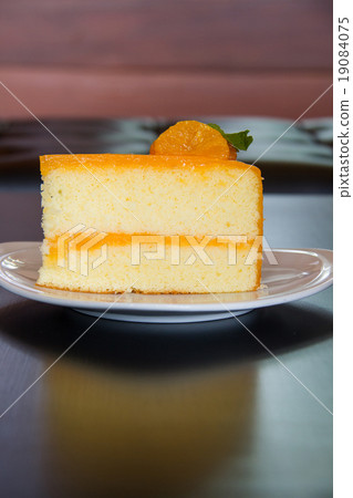 orange cake with orange topping in wooden dish 19084075