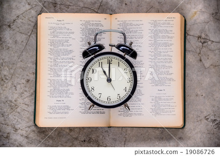 Retro alarm clock on holy bible on eleven o'clock. Retro alarm clock on holy bible on eleven o'clock. 19086726