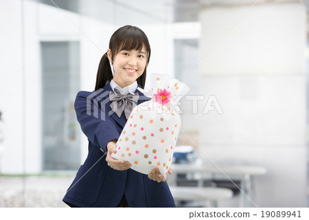 Girls high school girl posing in uniform holding a present Girls high school girl posing in uniform holding a present 19089941