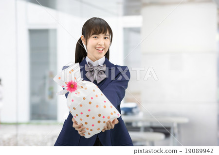 Girls high school girl posing in uniform holding a present Girls high school girl posing in uniform holding a present 19089942