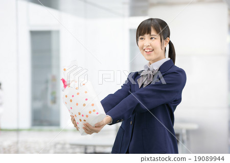 Girls high school girl posing in uniform holding a present Girls high school girl posing in uniform holding a present 19089944