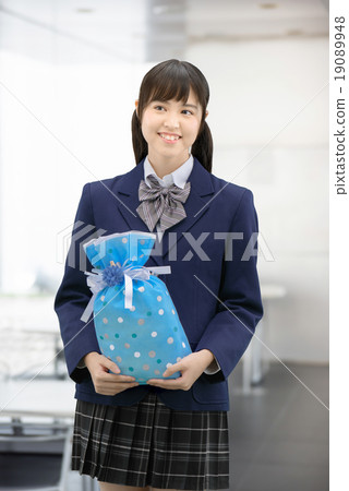 Girls high school girl posing in uniform holding a present 19089948