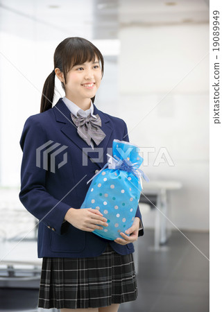 Girls high school girl posing in uniform holding a present Girls high school girl posing in uniform holding a present 19089949