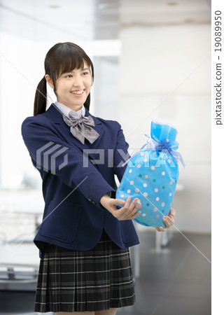 Girls high school girl posing in uniform holding a present Girls high school girl posing in uniform holding a present 19089950