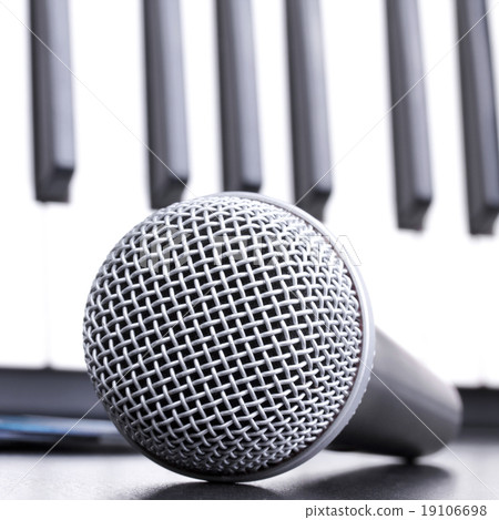 Microphone and piano keyboard on black table 19106698