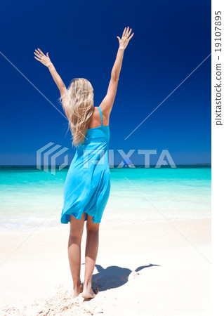 Happy blond girl on beach with outstretched arms Happy blond girl on beach with outstretched arms 19107895