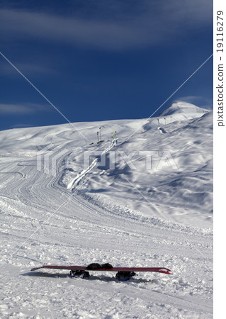 Snowboard in snow on ski slope at sun windy day Snowboard in snow on ski slope at sun windy day 19116279